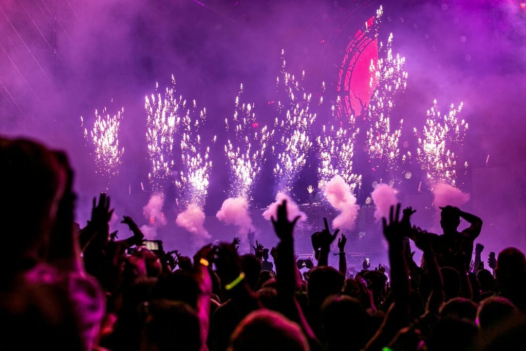 Vibrant EDM concert scene with fireworks, smoke, and enthusiastic crowd enjoying the music, turismo en Medellín