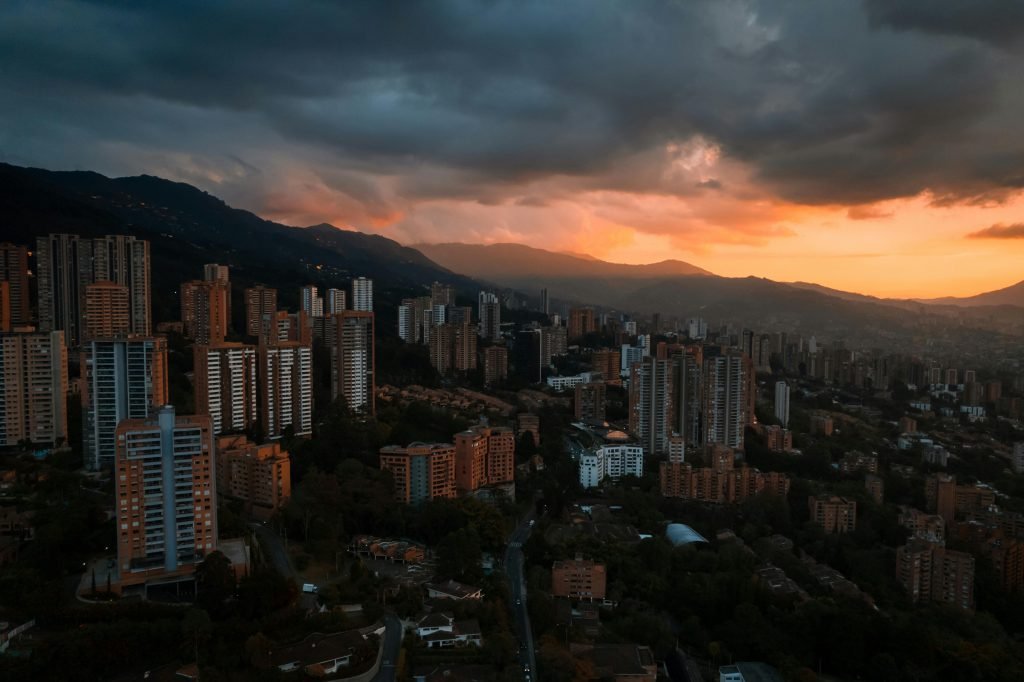 Stunning aerial view of Medellín's skyline at sunset with dramatic cloud formations creating a moody atmosphere, turismo en Medellín