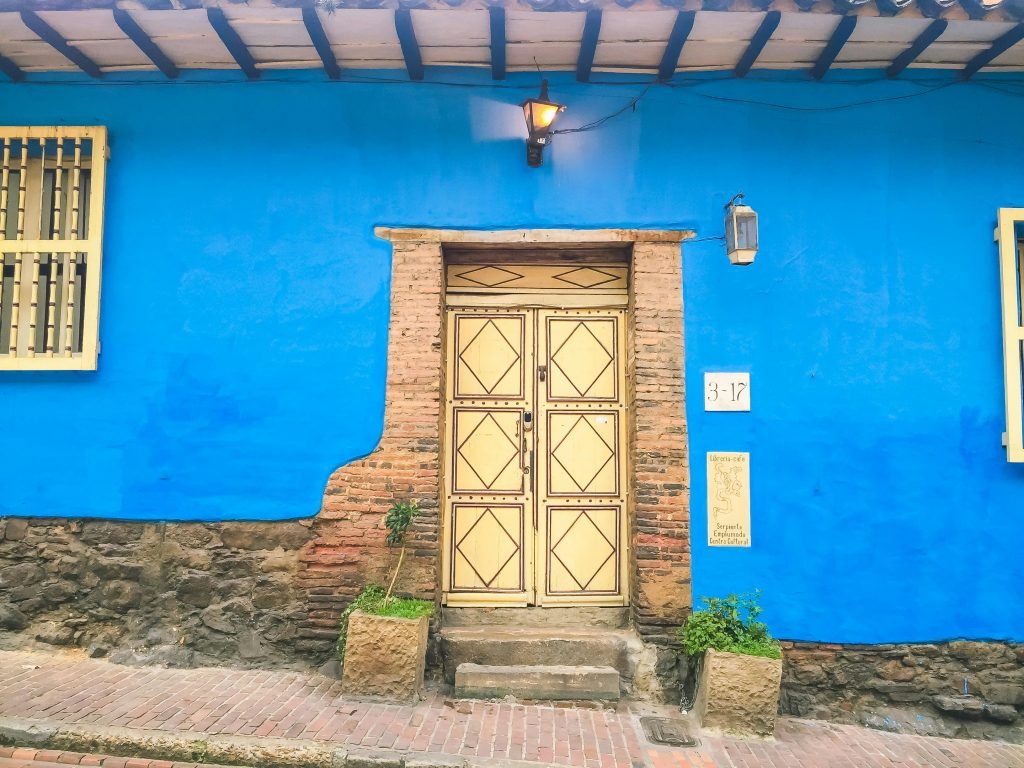 Colorful colonial architecture with a vibrant blue wall and traditional door in Bogotá, Colombia., tours en Colombia, organizar viaje