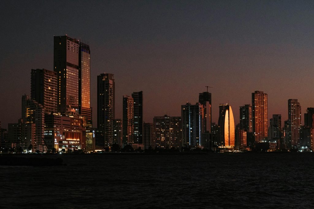 Explore the illuminated skyline of Cartagena de Indias against a serene dusk sky, featuring iconic skyscrapers, viajes a Cartagena