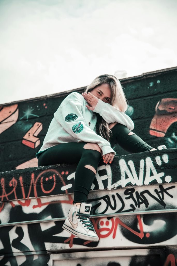Blonde woman in streetwear posing on graffiti-covered stairs in Medellín, turismo en Medellín