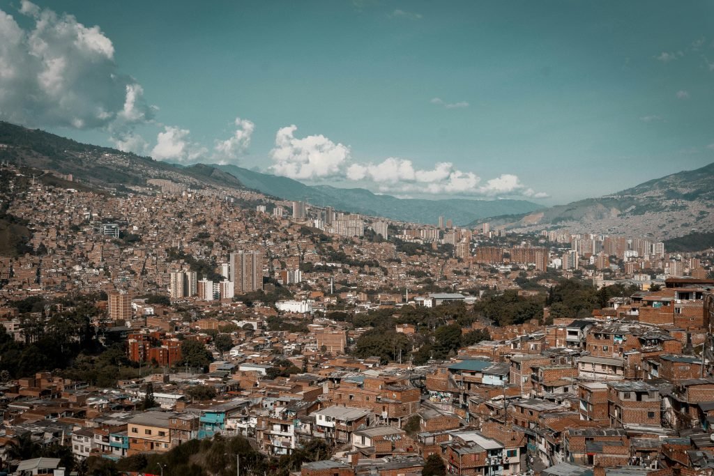 A panoramic aerial view of Medellín, showcasing its dense urban landscape against a backdrop of mountains, turismo en Medellín