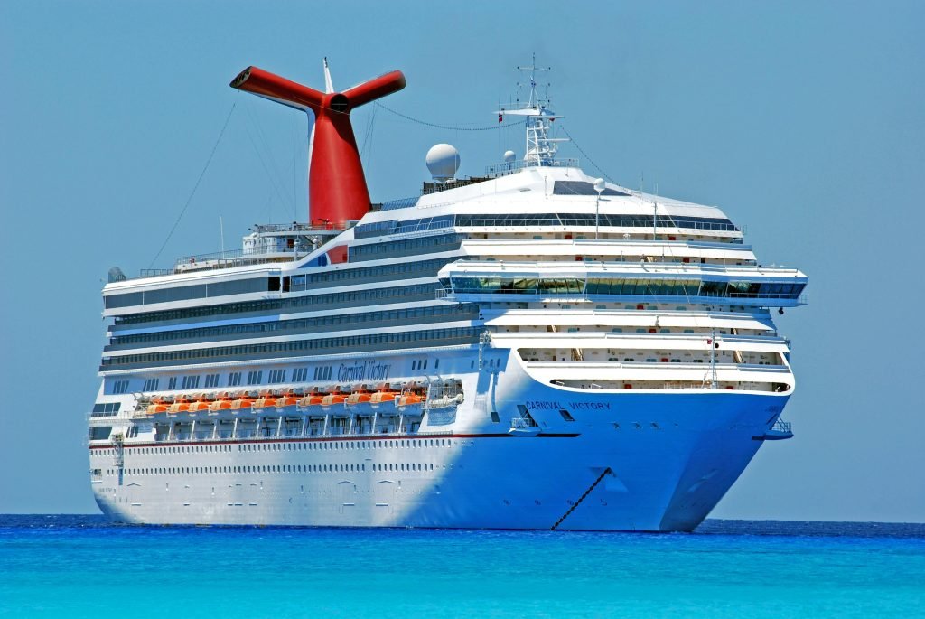 A large cruise ship gliding through clear blue ocean waters on a sunny day, cruceros
