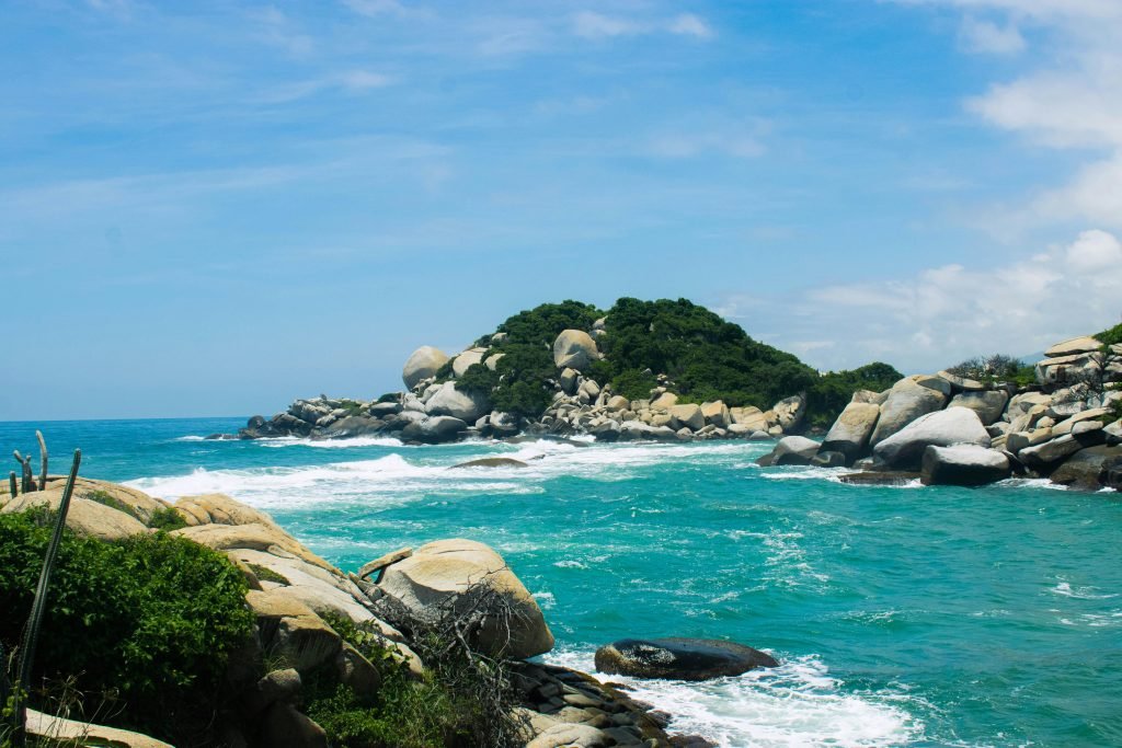 A picturesque view of Tayrona National Park with rocks and turquoise sea under a blue sky., Lugares turísticos de Colombia