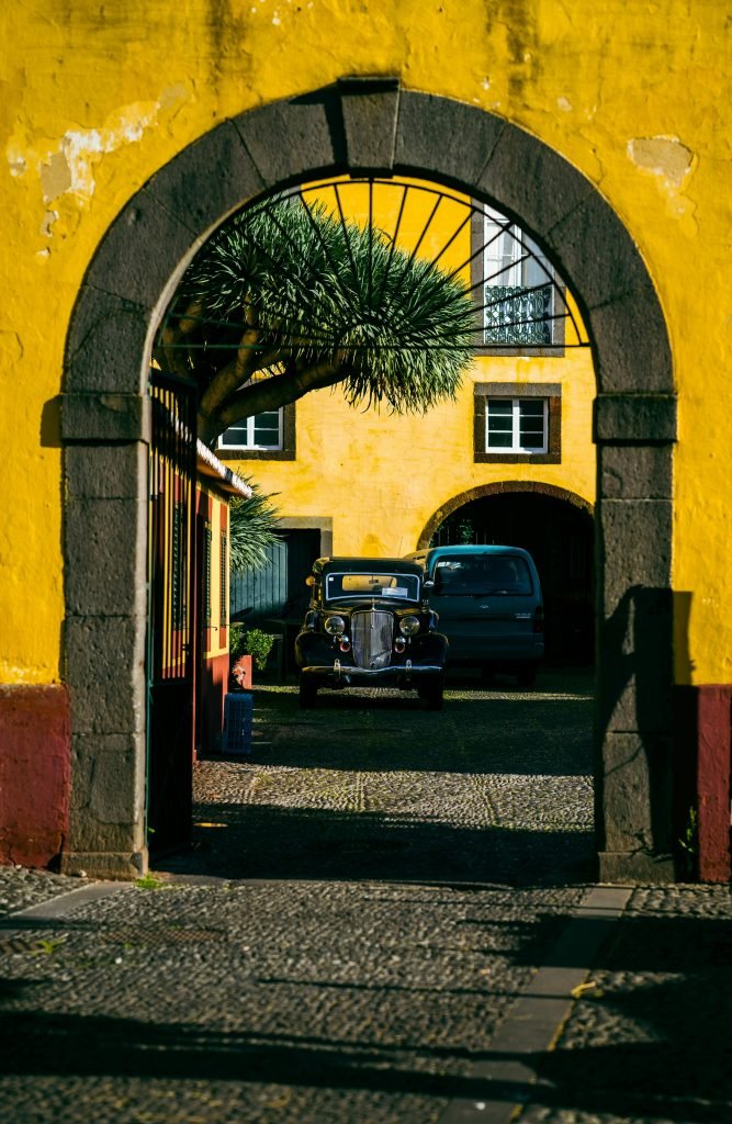 Classic car framed by stone archway on a sunny day in Portugal, Qué hacer en Cartagena, destinos
