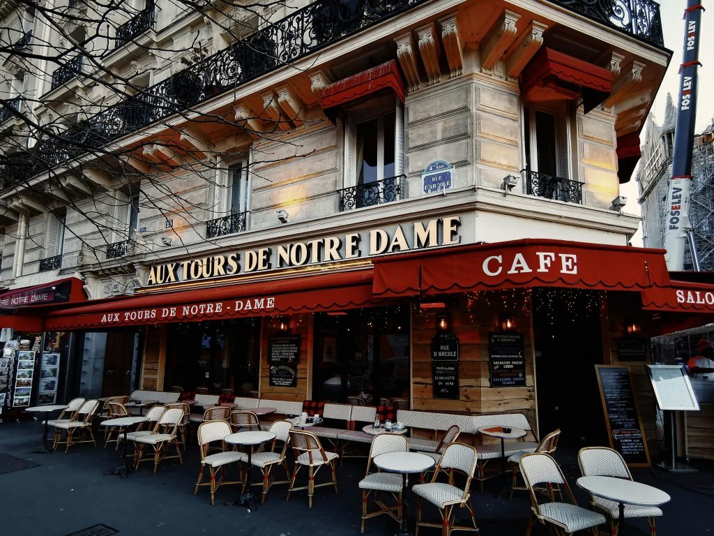 Parisian cafe Aux Tours de Notre Dame with empty outdoor seating in a vibrant urban setting, destinos