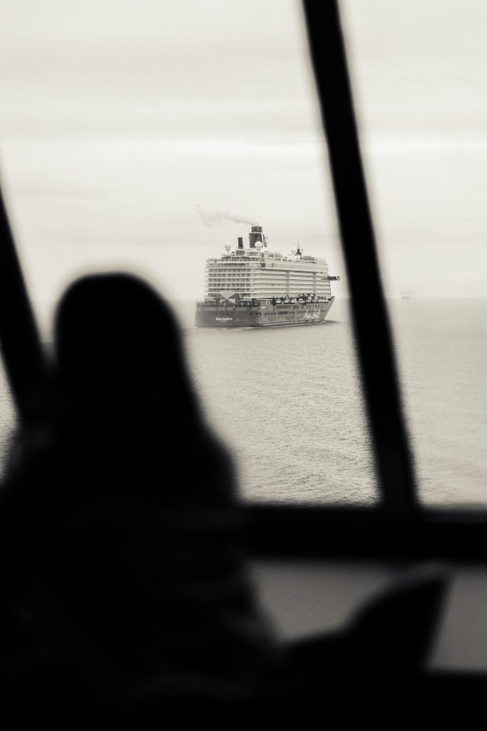 Black and white photo of a person's silhouette watching a cruise ship near Helsinki, cruceros