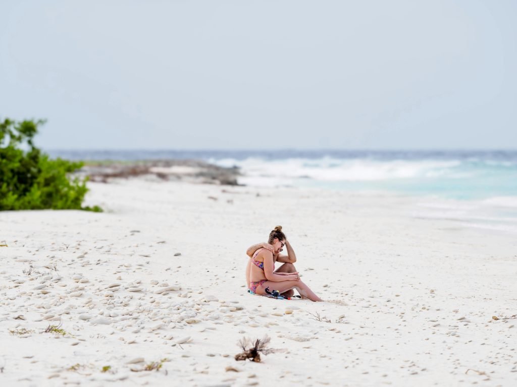A woman enjoys a peaceful moment on a pristine white sand beach, embracing the tranquility of the ocean, destinos