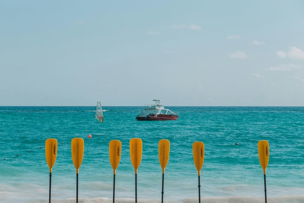 Vibrant beach scene in Punta Cana with paddles, boat, and windsurfing in turquoise waters, destinos