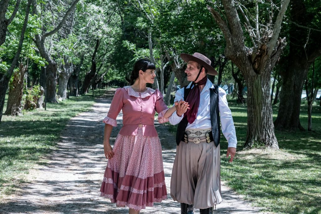 Couple in traditional gaucho attire dancing in a scenic park in Chascomús, Argentina, destinos