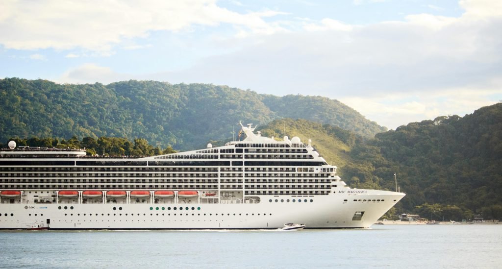 A majestic cruise ship sails through tranquil waters with lush hills in the background, perfect for travel enthusiasts, cruceros