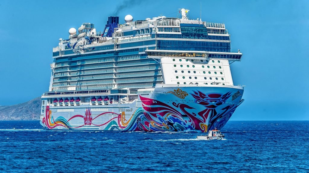 A colorful cruise ship sailing on the open sea under a clear blue sky. Ideal for tourism and travel themes, cruceros