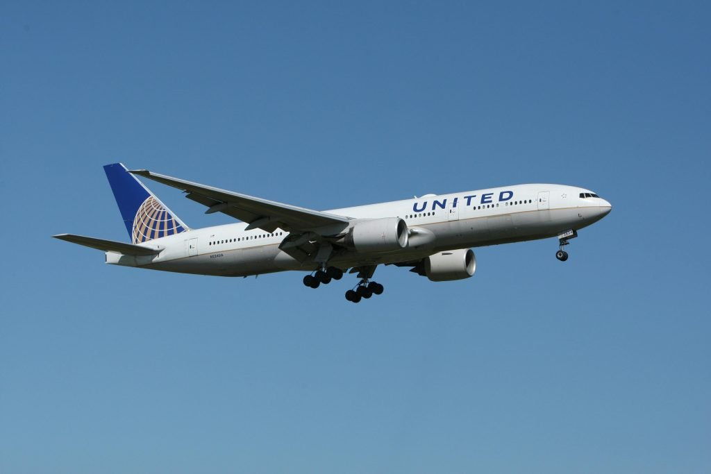 A United airliner flying against a clear blue sky, showcasing air travel., pasajes