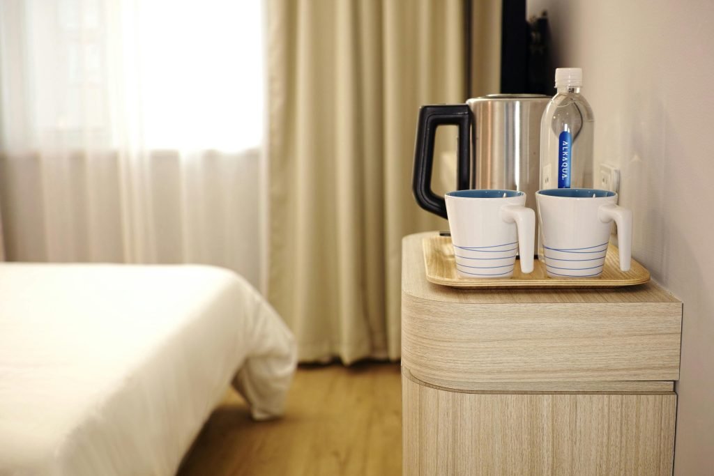 Contemporary hotel room featuring a neatly arranged beverage setup on wooden furniture., hotelería