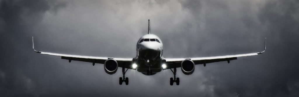 A dramatic view of an airplane landing with stormy clouds overhead, showcasing aviation in a monochrome scene., pasajes