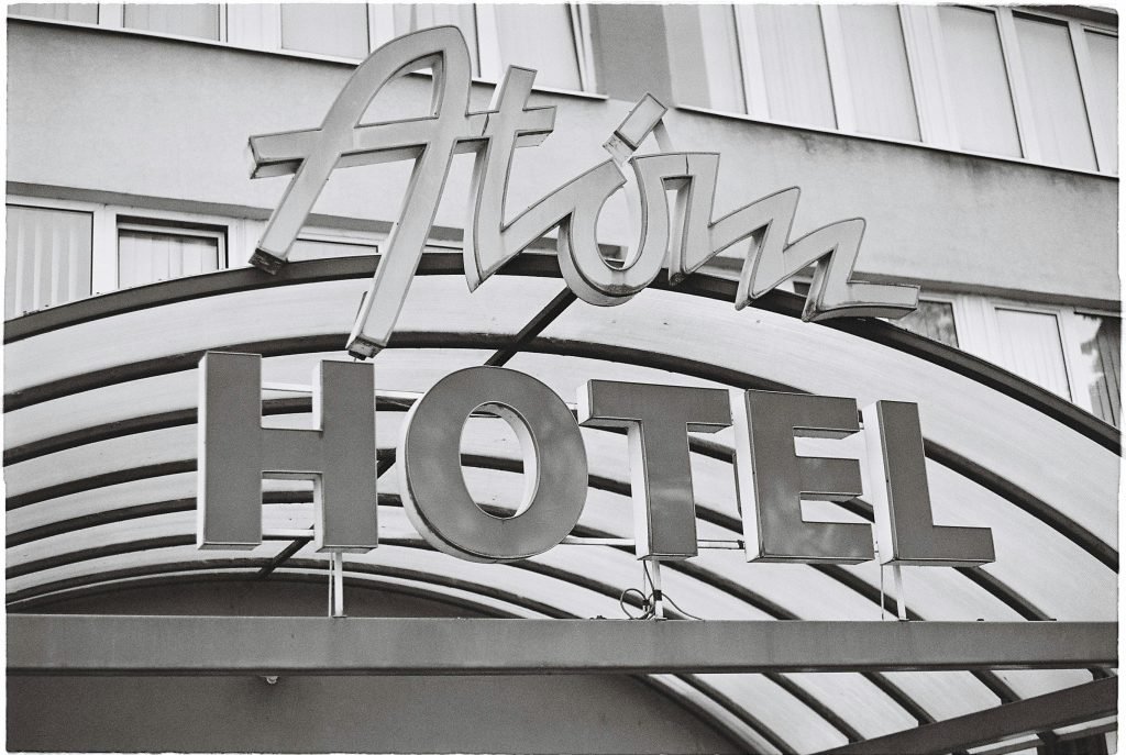 Black and white photo of the Atom Hotel entrance sign, showcasing vintage design., hotelería