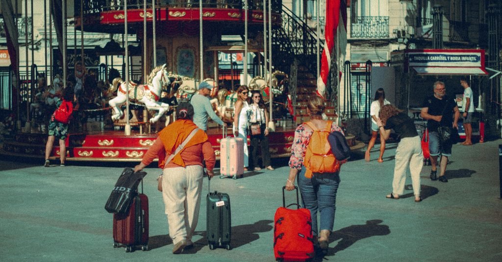 Travelers with suitcases explore a city park carousel on a sunny day., equipaje