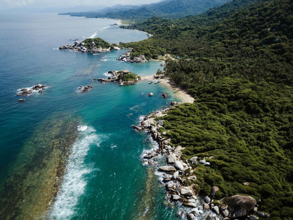 A breathtaking aerial view of the lush, rocky coastline in Colombia with crystal clear ocean waters., Tayrona