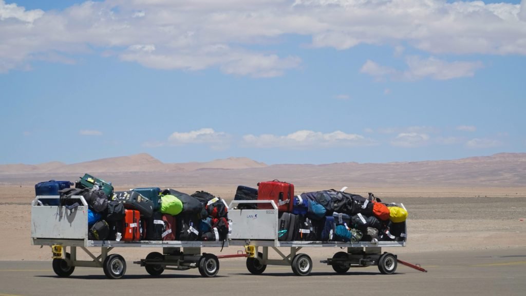 Luggage carts at airport loaded with colorful bags under clear sky. Outdoor travel scene., equipaje