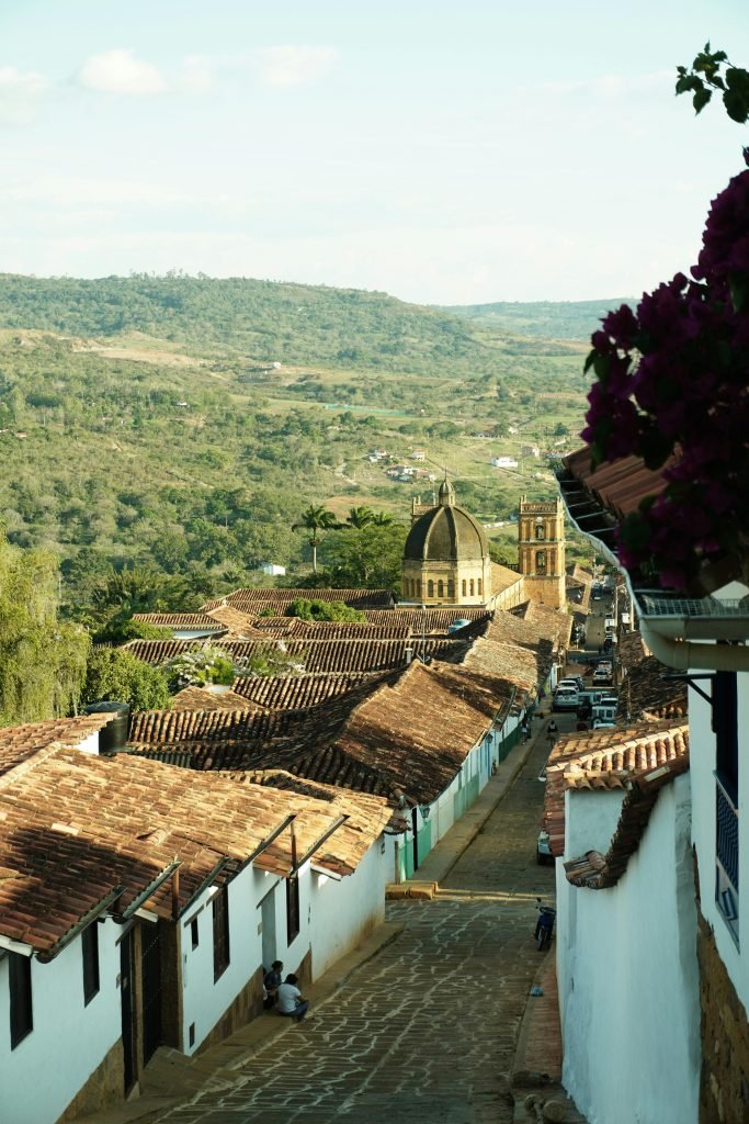 Picturesque view of colonial architecture and church in a historic town with mountain backdrop., requisitos para viajar a Colombia
