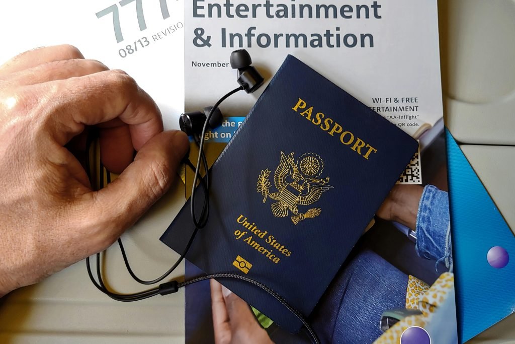 Close-up of US passport with inflight magazine and headphones on an airplane seat, ready for travel., visados