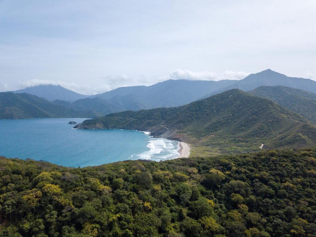 A breathtaking aerial view of Tayrona National Park's coastline with lush greenery and ocean waves, Tayrona