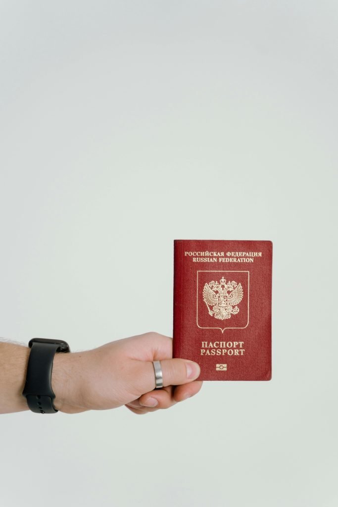 Close-up of a hand holding a Russian Federation passport on a white background., visados