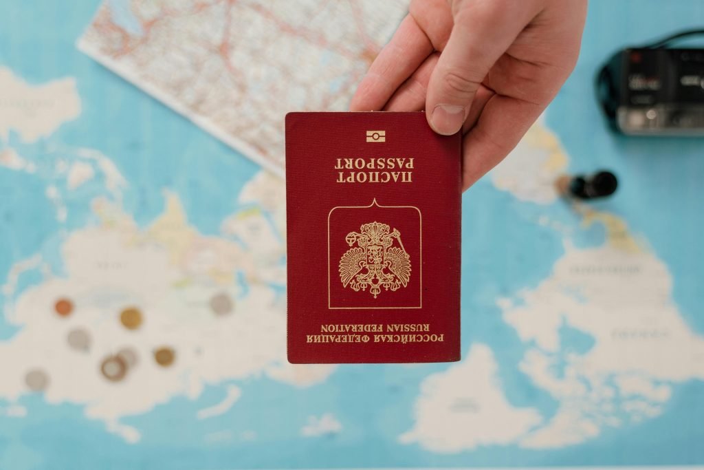 A hand holding a Russian passport over a map, suggesting travel preparation., visados