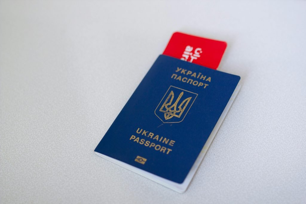 Blue Ukraine passport with airplane ticket on white surface. Travel concept., visados
