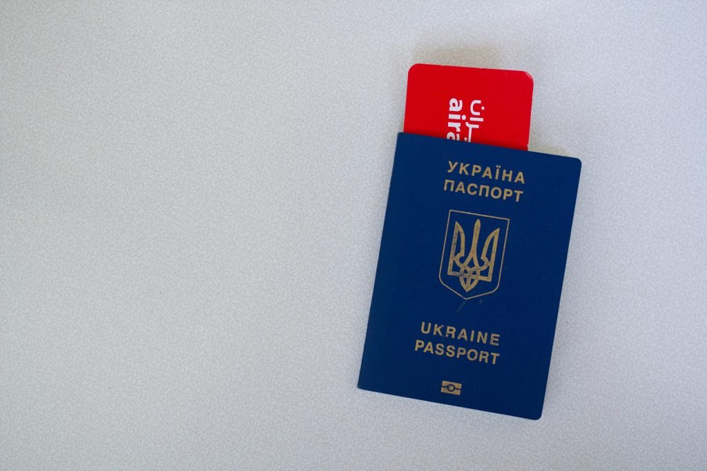 Close-up of a Ukrainian passport with an airline boarding pass on a white surface., visados
