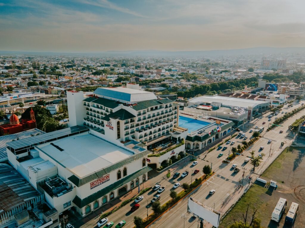 Drone shot capturing a vibrant cityscape with prominent hotel and busy highway. hoteles