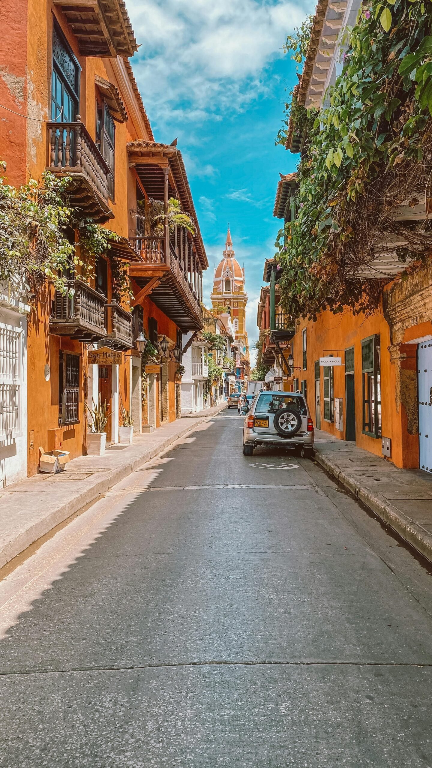 Charming street in Cartagena with vibrant buildings and cathedral in view, ideal for travel inspiration.