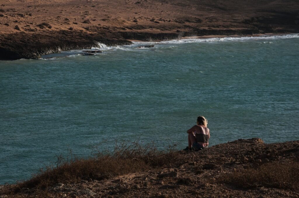 Woman gazes at the ocean from a cliff at Cabo de La Vela, capturing a serene summer moment. Guajira