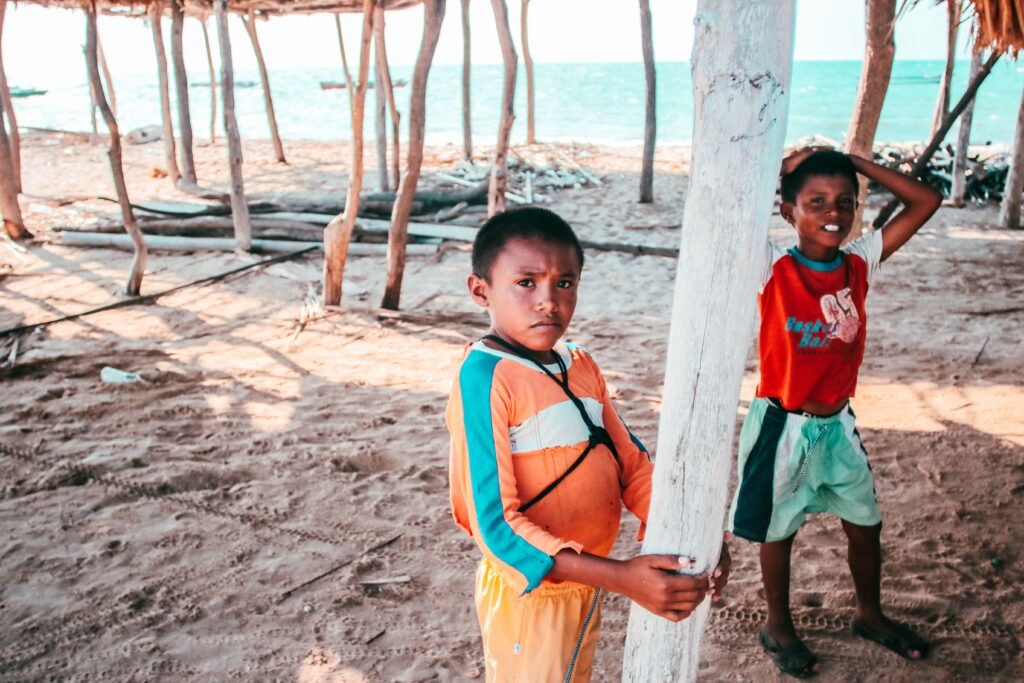 Two children playing by a beach hut in La Guajira, Colombia on a sunny day.