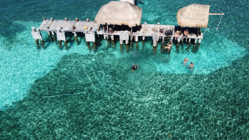 Breathtaking aerial view of Isla Mujeres pier with tourists and clear turquoise waters. islas del rosario