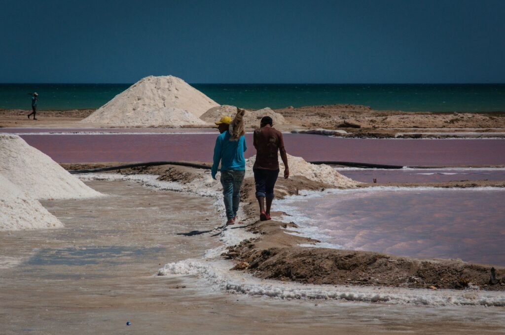 Two men walking through salt evaporation ponds in Manaure, La Guajira, Colombia on a sunny day.
