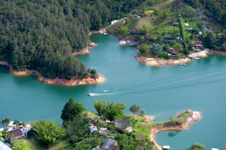 A breathtaking aerial view capturing a serene lake, surrounded by lush forests and a quaint village.