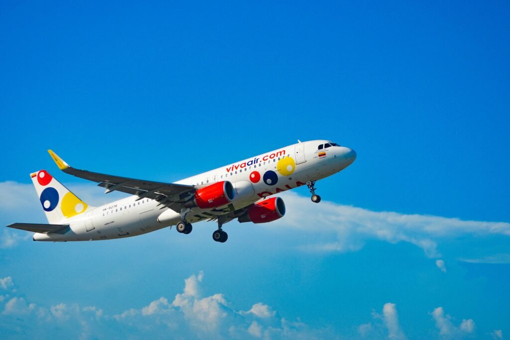 Airplane in flight over Colombia's blue skies, showcasing vibrant branding. vuelos