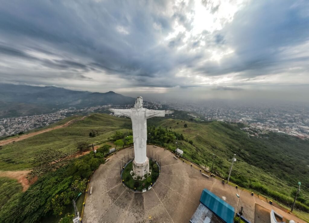Breathtaking aerial view of the Cristo Rey statue overlooking Cali, Colombia surrounded by lush greenery and urban landscape., Cali