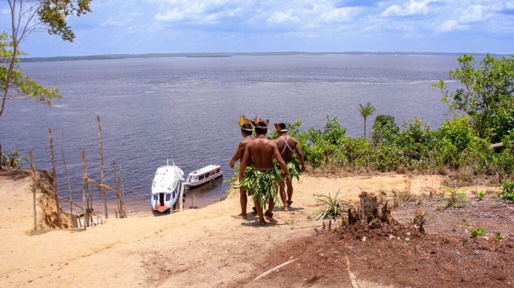 Indigenous men in traditional attire overlooking boats on the Amazon River., Leticia