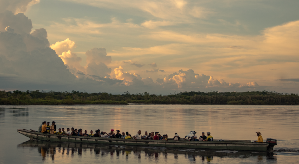 Serene image of a boat carrying people at sunset on a tranquil Colombian river., Leticia