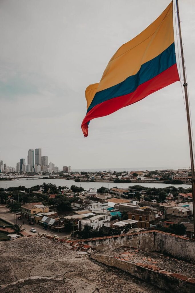 Colombian flag waving over urban landscape with skyline view.