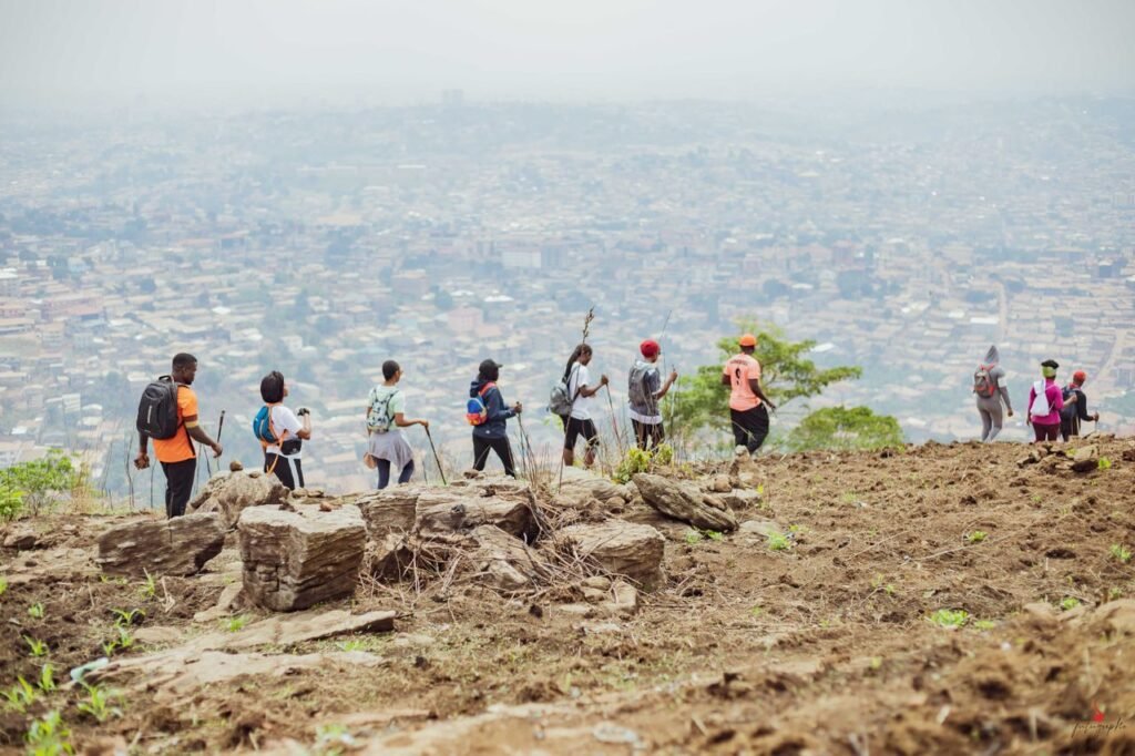 A group of hikers trekking on a rocky trail with a city view, showcasing adventure and teamwork. Trekking en Colombia