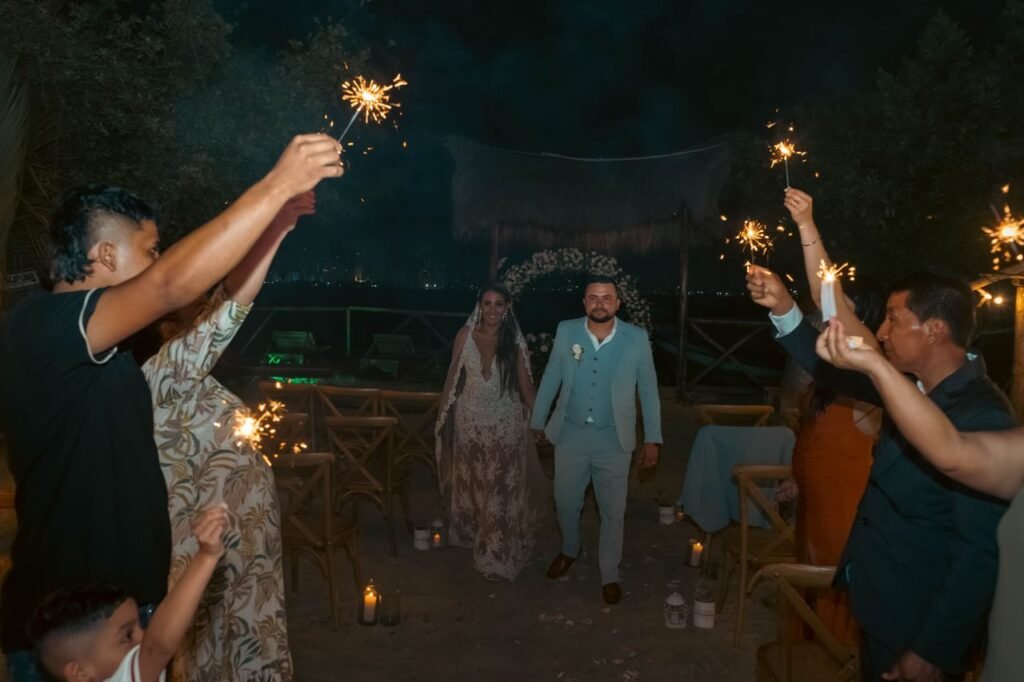 A couple's outdoor wedding ceremony with guests holding sparklers creating a festive atmosphere. luna de miel Colombia