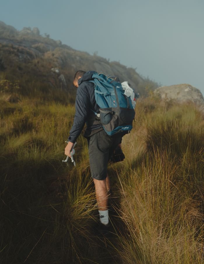 A solo adventurer hiking through misty hills with a backpack, capturing the essence of outdoor travel.